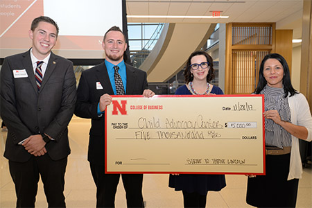 Dustin Schmidt, a senior business administration major from Tekamah, Nebraska, and Burcham present a check for $5,000 to Paige Piper and Christy Pange of the Child Advocacy Center.