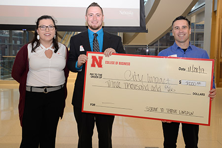 Dustin Schmidt, a senior business administration major from Tekamah, Nebraska, and Burcham present a check to Paige Piper and Christy Pange of the Child Advocacy Center.