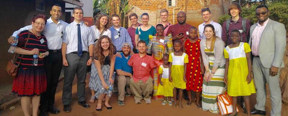 Group shot of Uganda study abroad students, faculty and Madame Benedicta with children