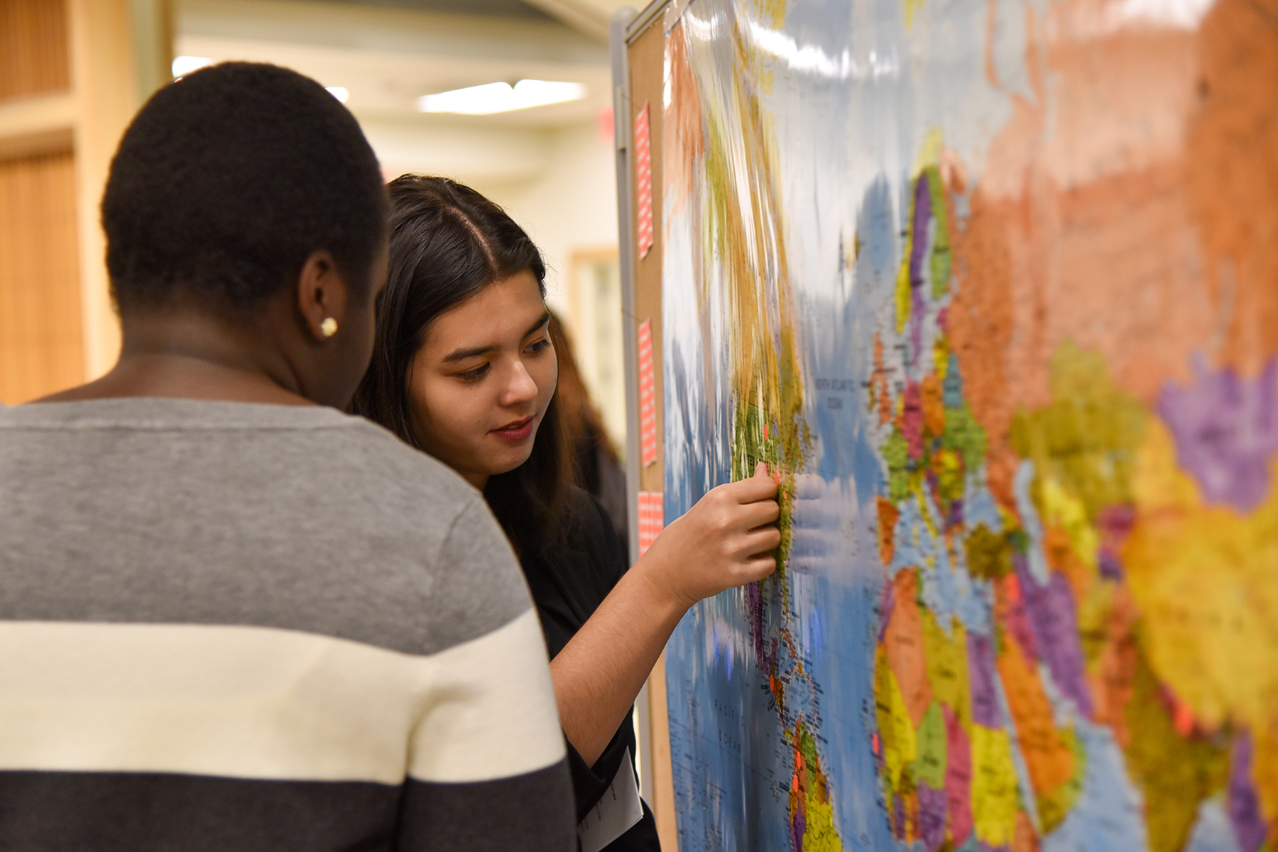 Two students marking their hometown on a world map.