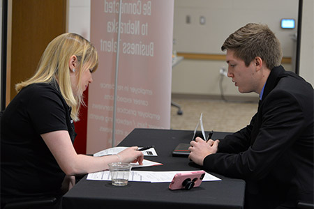 Nicole Cavin, campus recruiting specialist at Deloitte, walks through a student’s résumé with him.
