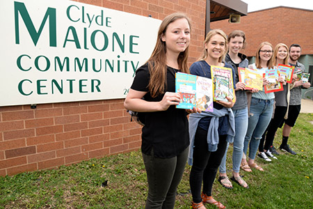 Honors Academy students pose with children's books about to be distributed at the Malone Community Center.