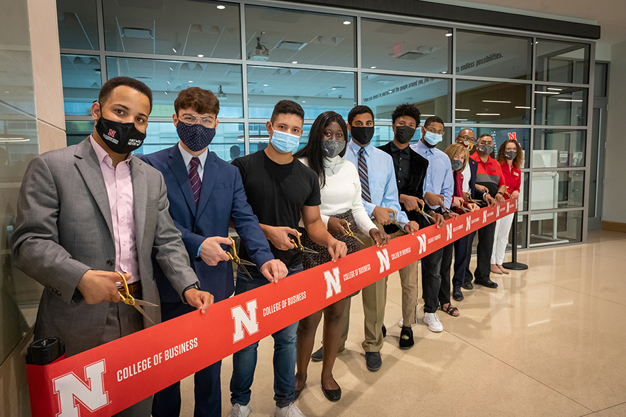student leaders and members of the college of business inclusive excellence advisory board cut the ribon in front of the diversity and inclusion gathering space.