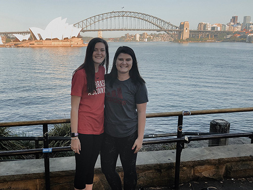 Anna and Hallie Lockhart stand in front of the Sydney Opera House and Harbour Bridge. 