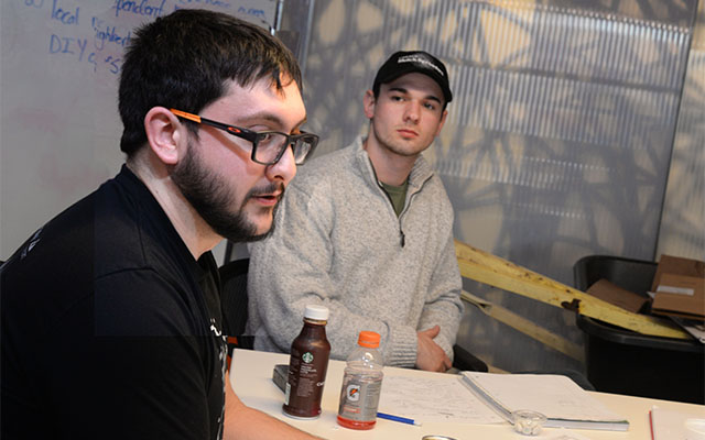 Hofeling (right) listens to experiences of mentor Alex Kuklinski, founder of fyiio, while trying to solve issues for his team's wheelbarrow business.