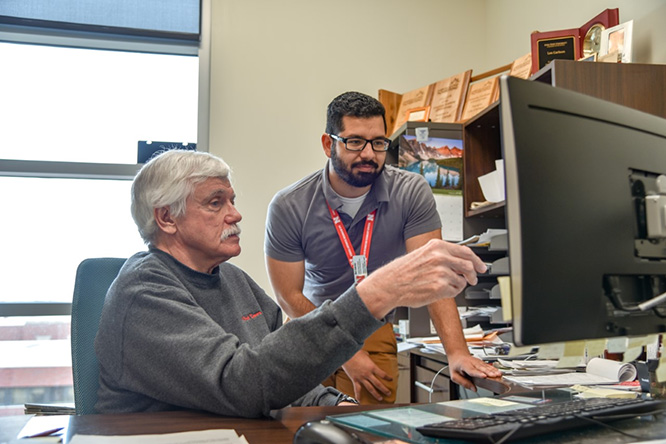 Les Carlson works with Nery Cabrera to upoad video lectures for students during his transition to remote learning presentations. 