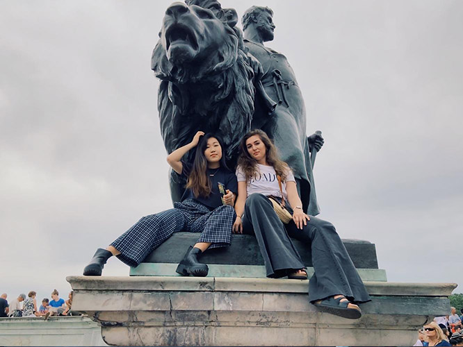 Jessica and Ariel sit with a Victoria Memorial statue before the Changing of the Guards outside Buckingham Palace.