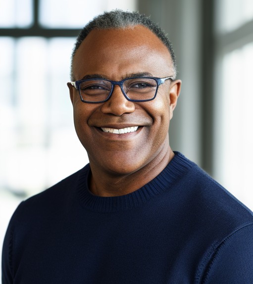 Jamie Williams; Man wearing a navy sweater in a bright room with large windows and blurred background.