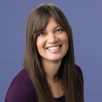 Erin Bond; Woman with straight, long brown hair wearing a purple top, set against a blue background.