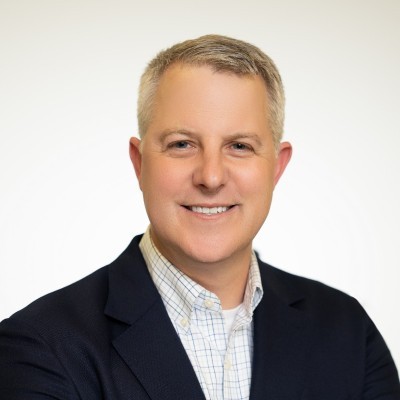 Todd Cruise; Man in a blazer and checkered shirt against a plain white background.