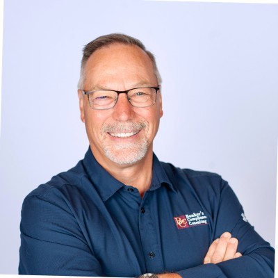 David Dickinson; Blue-shirted person with arms crossed, logo visible on the shirt; face blurred.