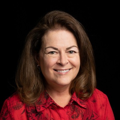 Donna Dudney; woman with dark wavy hair wearing a red shirt with dark background