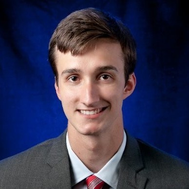 Darren Johnson: Man in a suit and tie against a dark blue background, face blurred.