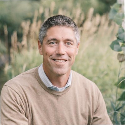 Shawn Radtke; Man in a tan sweater in an outdoor setting with blurred greenery in the background.