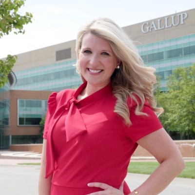 Lindsay Spehn; Woman in red dress standing outdoors near Gallup office building.