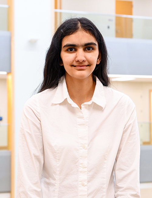 Person in a white shirt indoors, blurred face in a modern building setting with soft lighting.