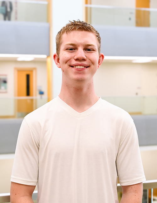 Man in a white shirt standing in a modern indoor space with neutral colors.
