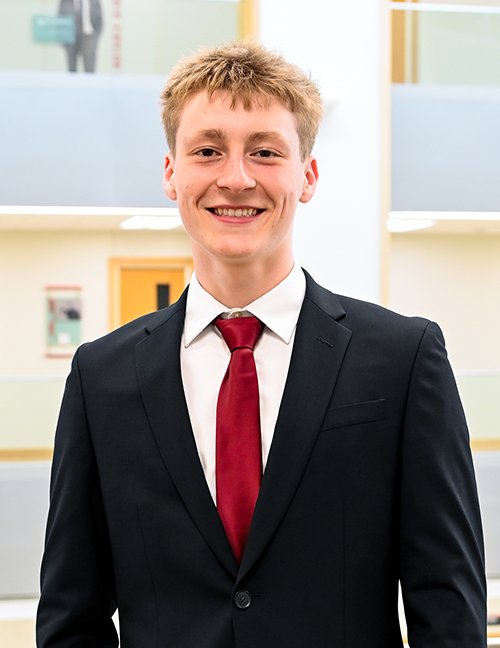Man in a suit with a red tie in a modern indoor setting, face blurred.