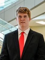 Young man in a suit with a red tie standing in a modern indoor space.