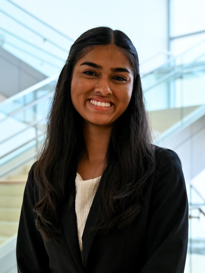 Smiling woman in formal attire with a staircase in the background.