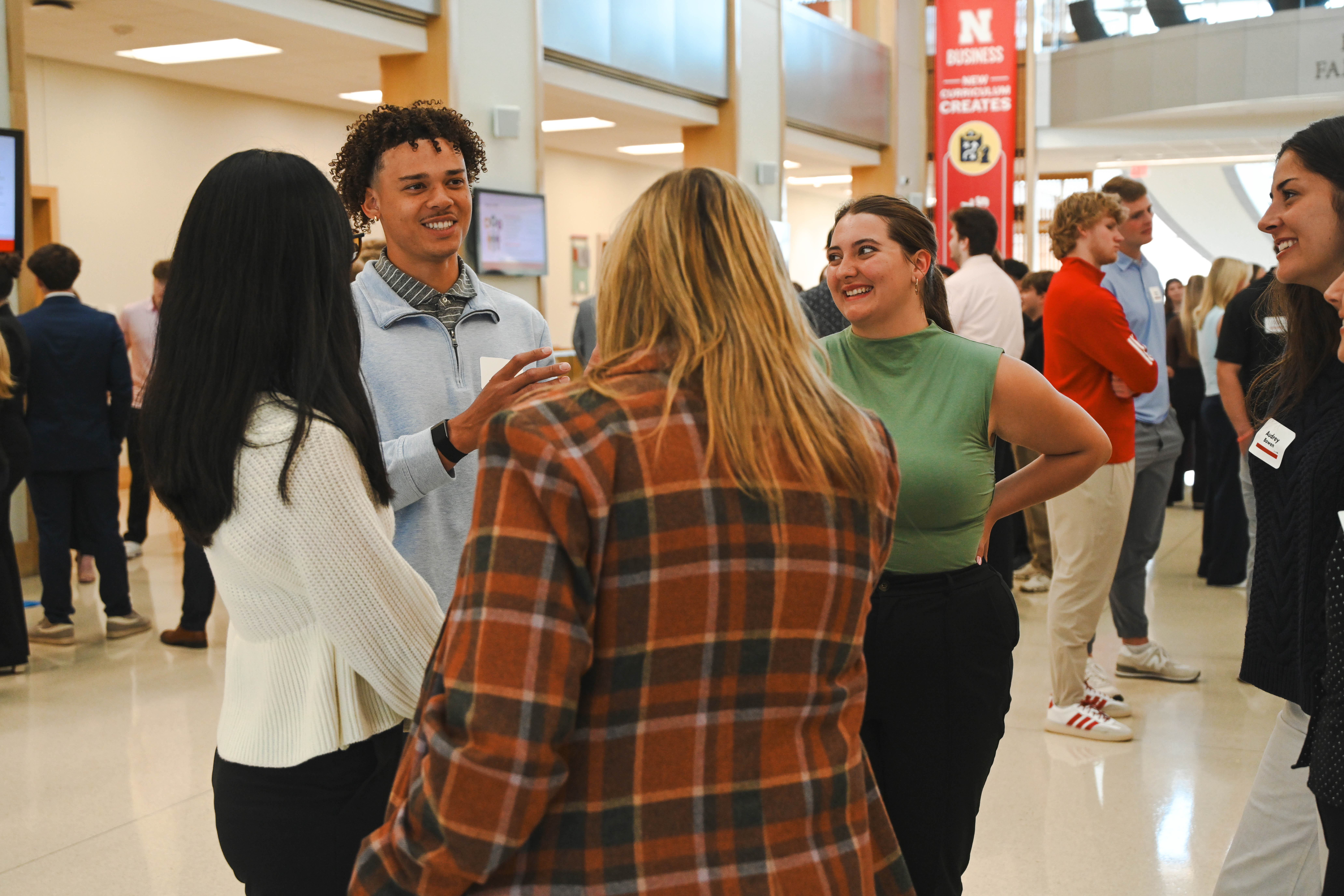 People in casual attire chatting in a bright indoor event space.