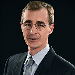 Man in formal suit with blurred face against black background.