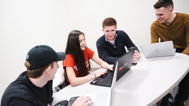 Kat Woerner (center) and her teammates discuss their shoe company's strategy for the next round of the Business Strategy Game