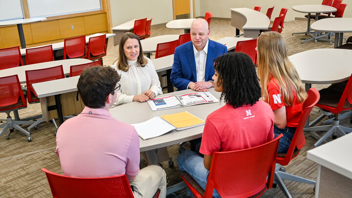 Group discussion in a classroom with red chairs and desks.