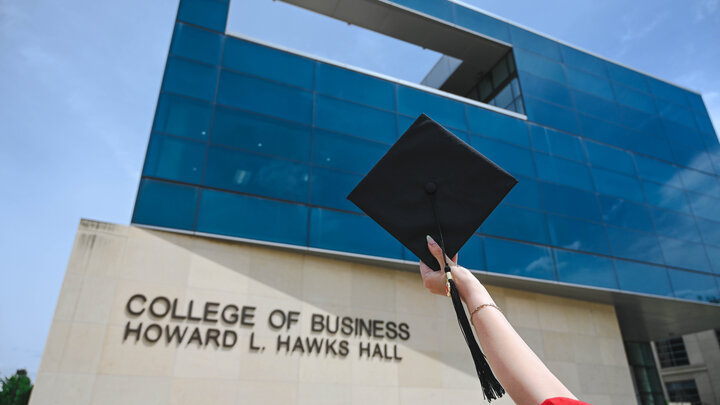 Graduation cap raised in front of College of Business, Howard L. Hawks Hall.