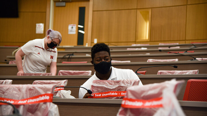 Amanda Colborn, building operations manager, and Ulysses Johnson III, student worker, help prepare Howard L. Hawks Hall classrooms for social distancing standards prior to the fall semester.