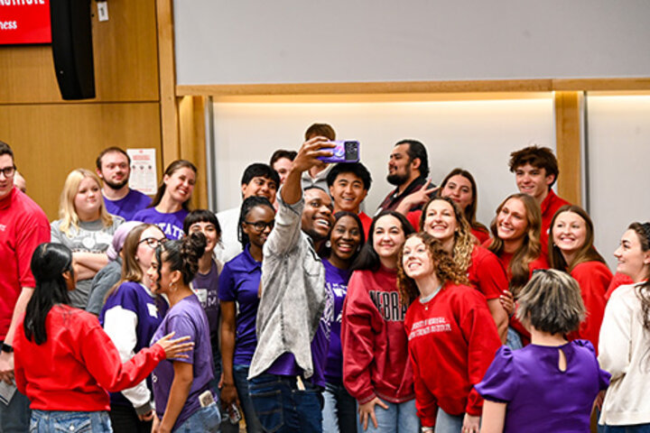 Group of people in colorful clothing taking a selfie in a classroom setting.