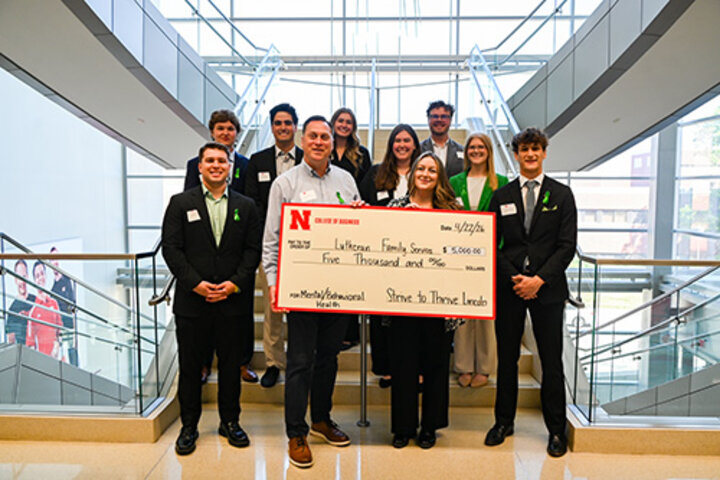 Group holding a large check in a modern building with glass and metal accents.