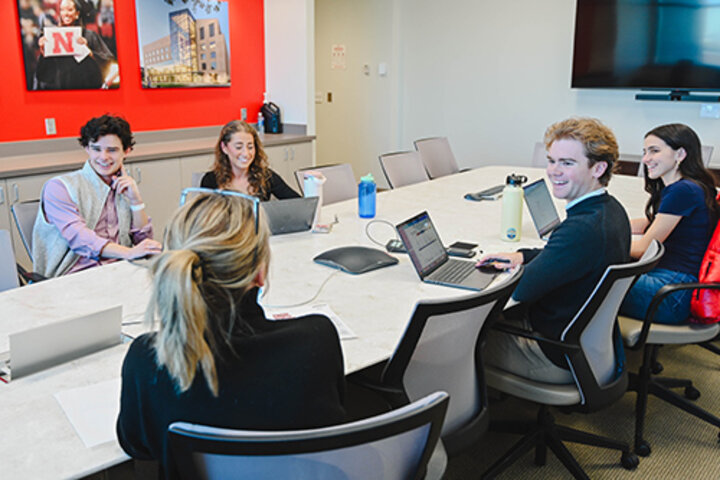 Students around a conference room table working on their presentation