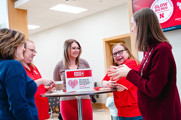 women standing around a table talking at Glow Big Red kickoff event in Hawks Hall