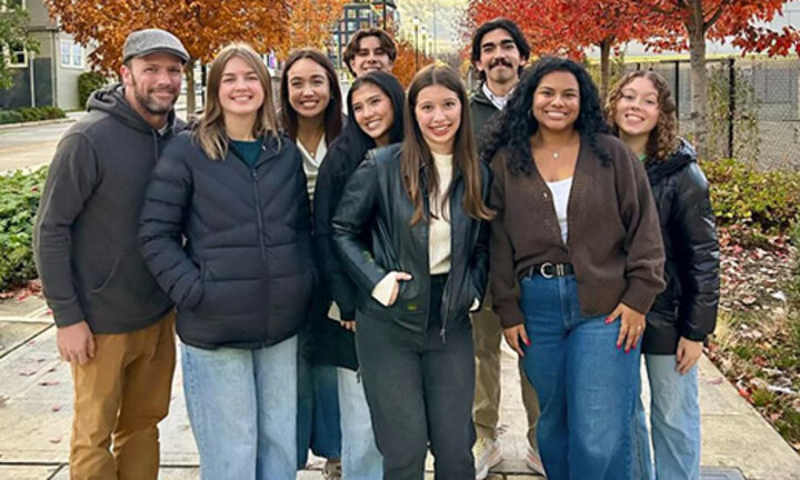 Students pose in a group in front of the Space Needle with fall foliage in the foreground