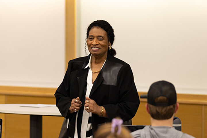 Speaker addressing an audience in a classroom setting.