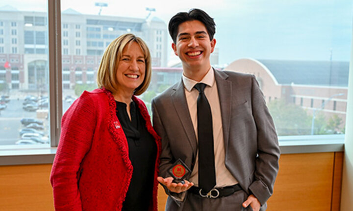 Kathy Farrell gives Carlos a Dean's Coin in her office
